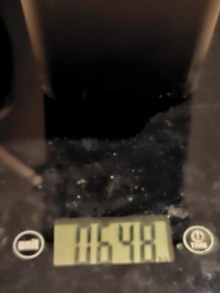 Eine digitale Waage zeigt das Gewicht 116,48 an. Über der Waage ist ein dunkler Behälter oder Topf zu sehen.