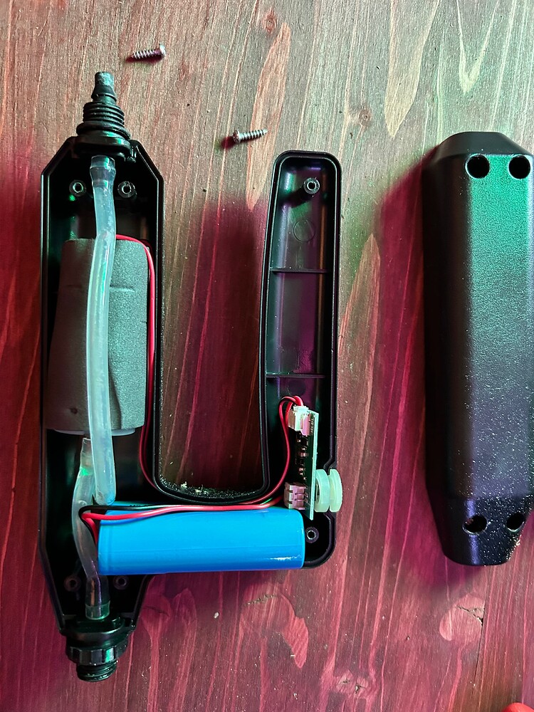 Zerlegtes Gerät mit Batterie und Platine auf Holzhintergrund.