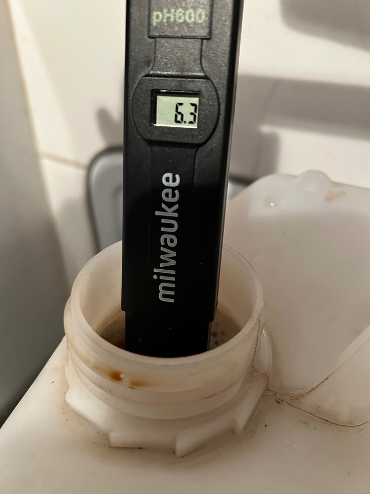 Ein pH-Messgerät von Milwaukee mit der Anzeige "6.3" steckt in der Öffnung eines weißen Behälters, der eine braune Flüssigkeit enthält.